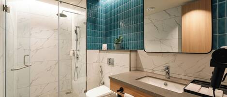 A modern bathroom with a glass shower enclosure, a white toilet, a sink with a mirror, and a towel rack.
