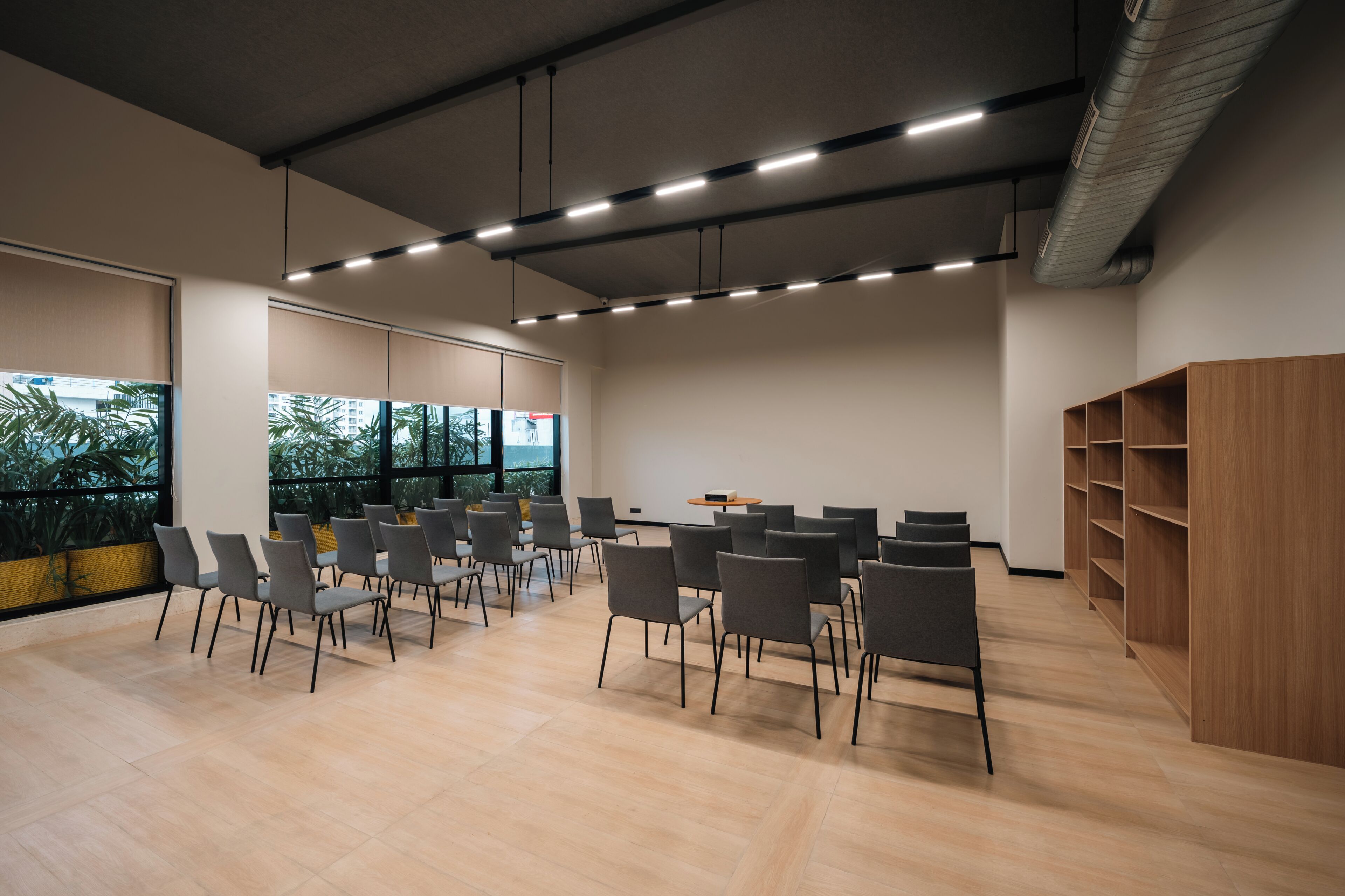 A conference room with a long table, chairs, and a wooden shelving unit.