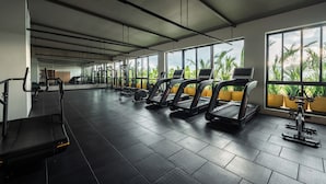 Une salle de sport équipée de tapis de course, de vélos d’appartement et d’appareils de musculation.