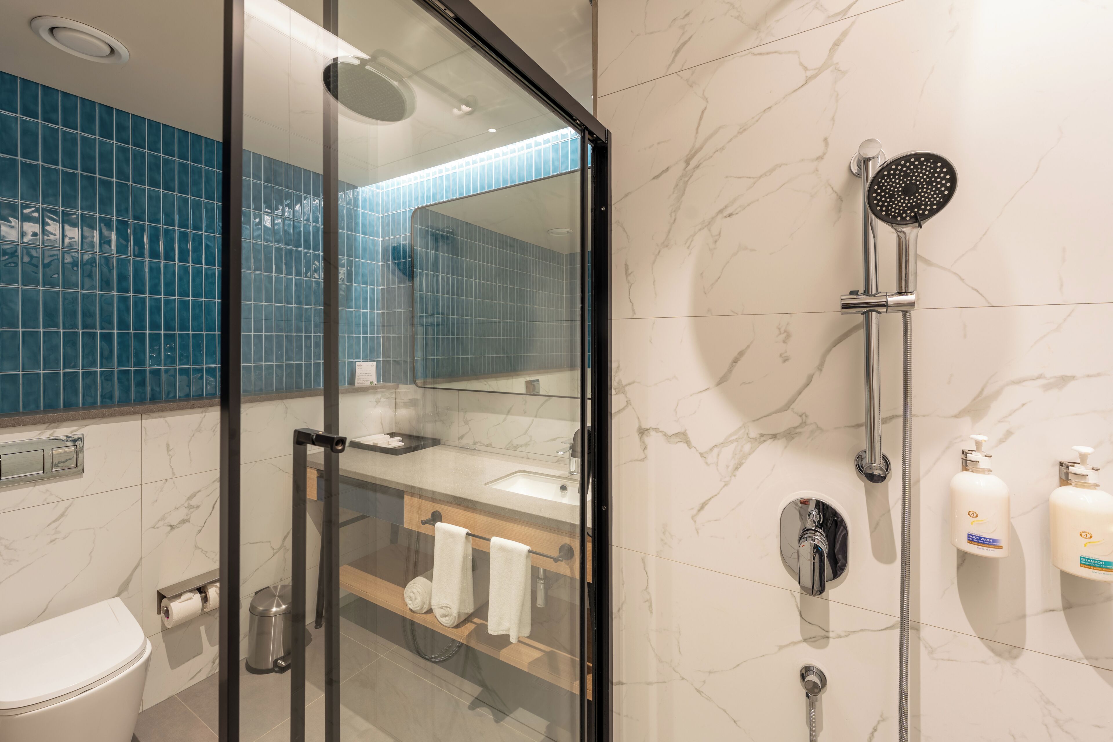Een moderne badkamer met een douchecabine van glas, een toilet en een wastafel met spiegel.