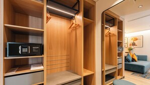 Une chambre d’hôtel moderne avec un placard en bois, un four à micro-ondes et un canapé bleu.