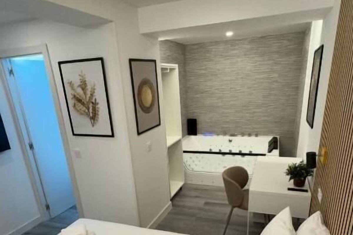 A modern hotel room with a neatly made bed, a small desk, and a view of the bathroom.