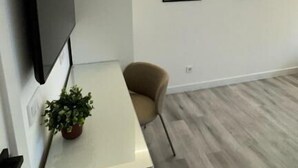 A modern living room with a flat-screen TV mounted on the wall, a beige sofa, a small potted plant, and two framed artworks on the wall. - jacuzzi rooms (Madrid)