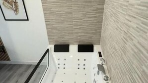 A modern bathroom with a freestanding bathtub, a wooden floor, and a textured wall. - jacuzzi rooms (Madrid)