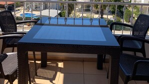 A balcony with a table and chairs, overlooking a residential area with houses and a mountain in the background. - Paddys Pansiyon (Fethiye)
