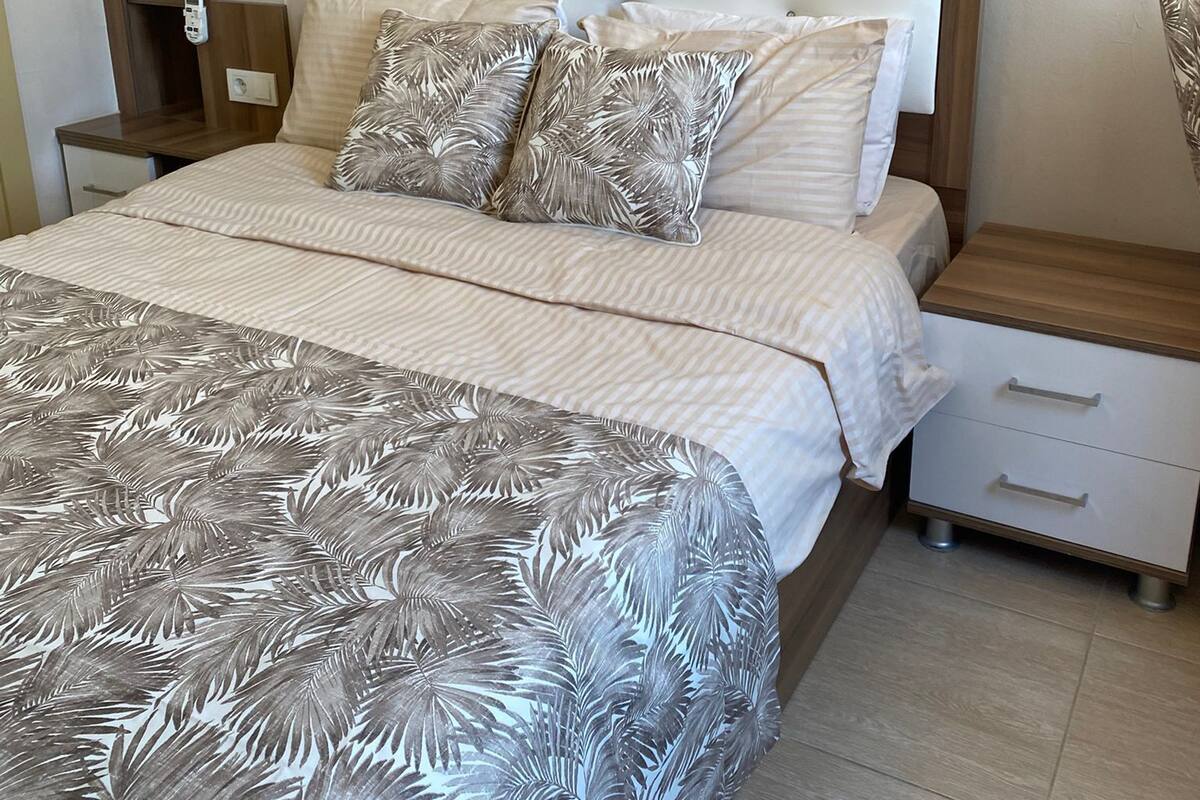A bedroom with a bed, nightstands, a wardrobe, and a wall-mounted air conditioner.