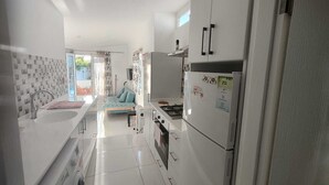 A modern kitchen with white cabinets, a built-in oven, and a refrigerator. - Paddys Pansiyon (Fethiye)