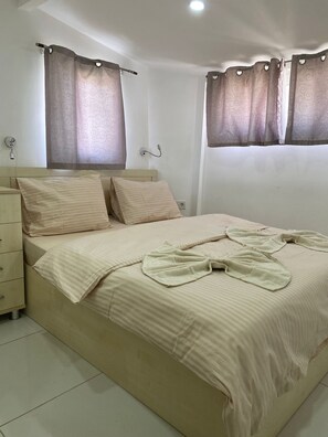 A neatly made bed with a striped bedspread, a bedside table, and a wall-mounted light fixture.