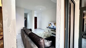 Een moderne woonkamer met een modulaire bank, een flatscreen televisie en een eethoek met een glazen tafel.