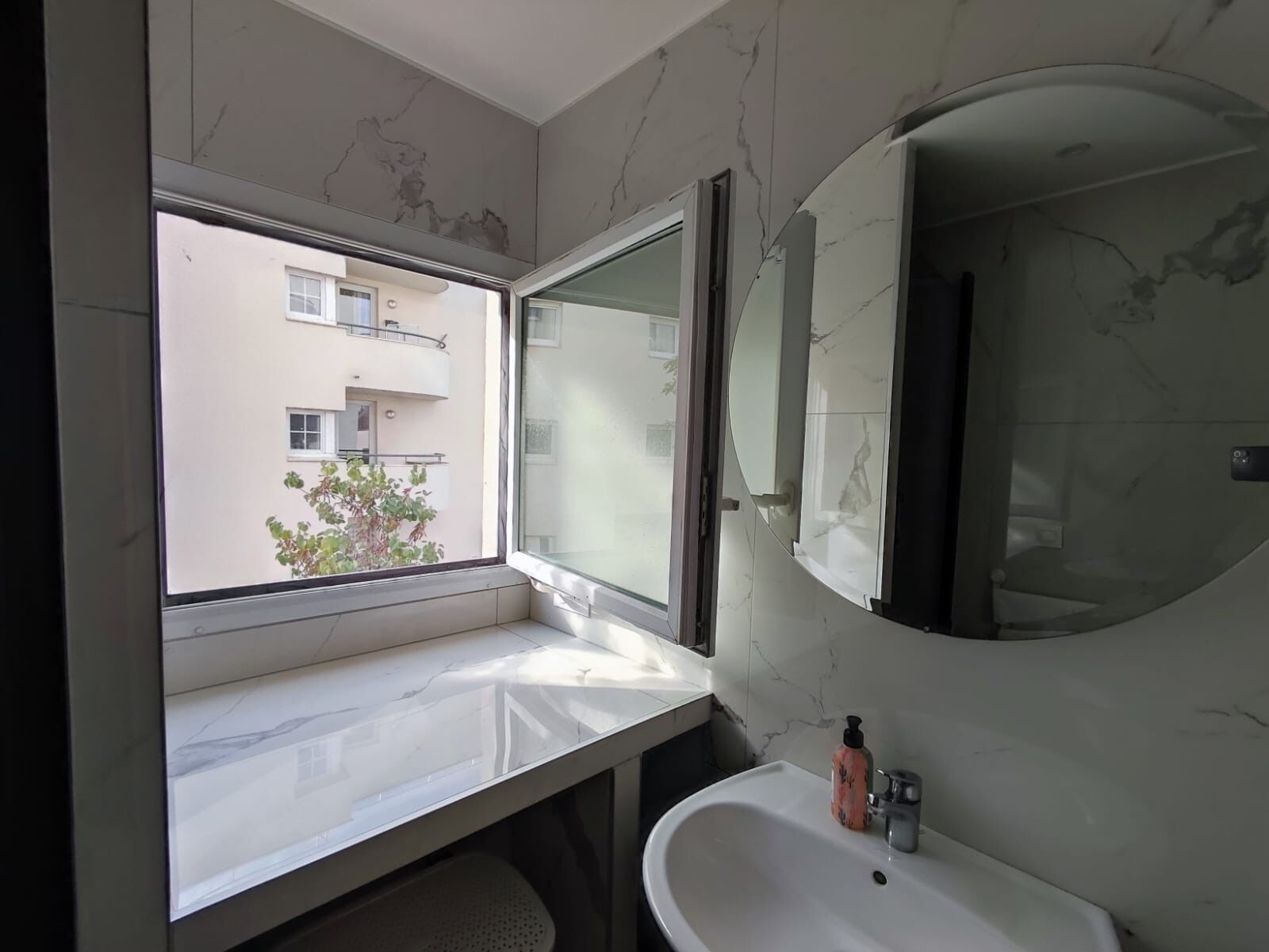 Un baño con un ventanal grande, un lavabo y un espejo.