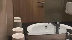 Une salle de bain moderne avec deux lavabos, un miroir et une porte en bois.
