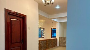 A hallway with a wooden door marked '103', a chandelier, and a patterned wall. - The Zurfi's Hotel (Kargil)