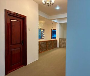 A hallway with a wooden door marked '103', a chandelier, and a patterned wall.