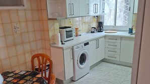 A compact kitchen with a washing machine, a microwave, and a coffee maker. - 2-Bedroom Apartment Puerto de la Cruz – Minimum Stay 4 Months, Quiet Location (Puerto de la Cruz)