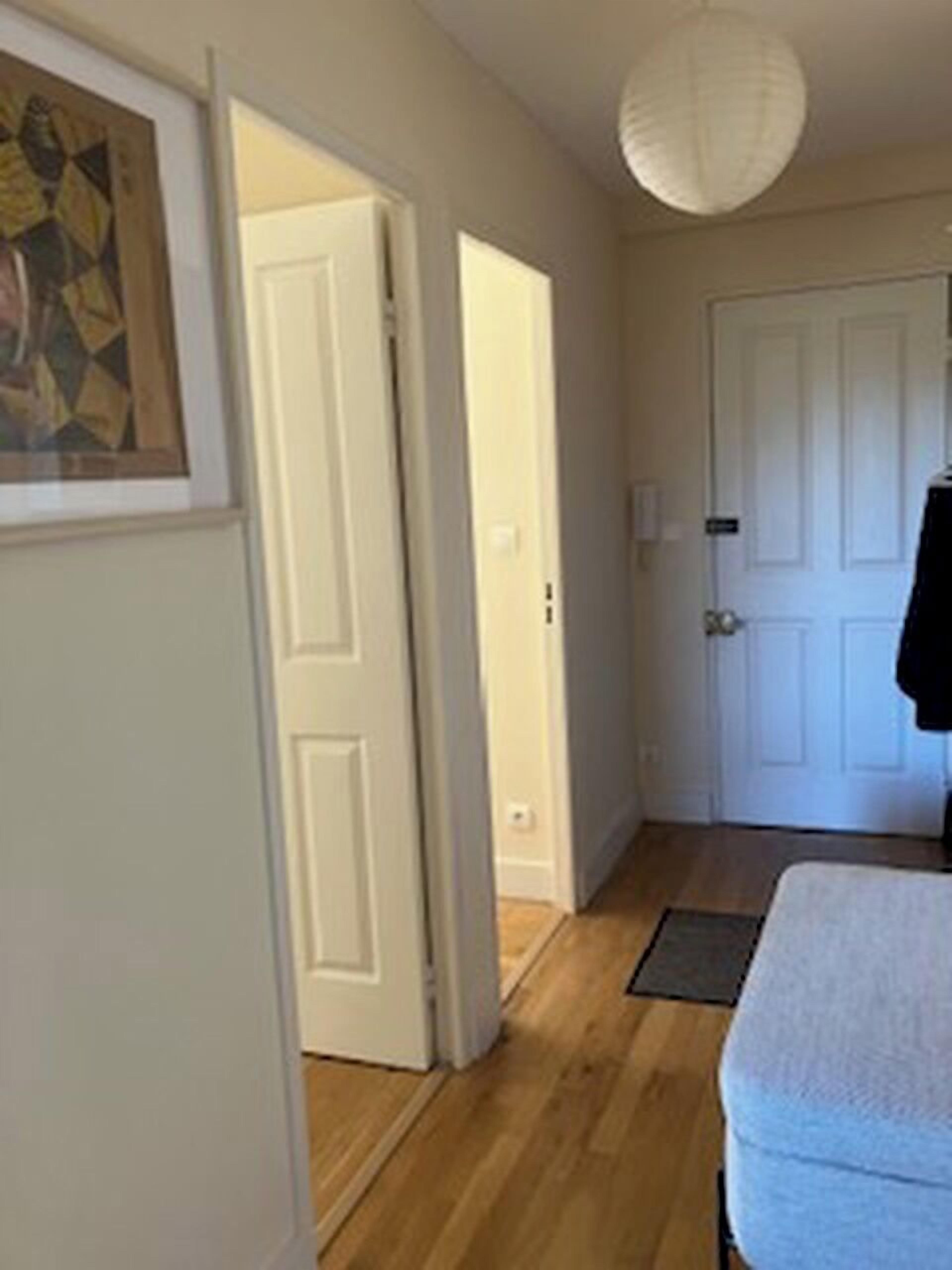 Ein Zimmer mit Holzboden, einer weißen Tür und einem Gemälde an der Wand.