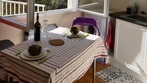 Ein Essbereich mit Tisch für zwei Personen, einem Fenster mit Blick auf Grünflächen und einer Hängelampe.