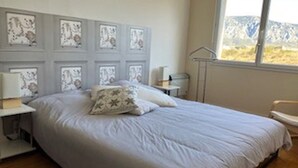 Ein Schlafzimmer mit Bett, Nachttisch, Stuhl und einem Fenster mit Bergblick.