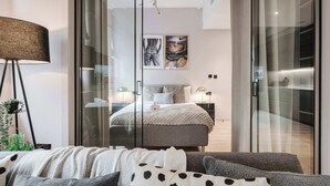 A modern bedroom with a glass door closet, a bed with a gray and white duvet, a floor lamp, and two framed pictures on the wall. - Central 2-Bed, Walk to Chinatown & Theatres (Greater Manchester)