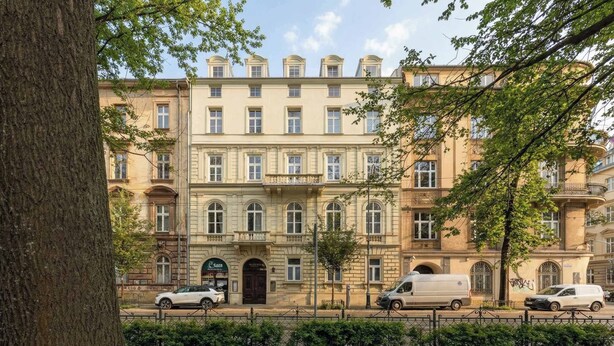 A multi-story building with a classic architectural style, featuring a central entrance with a dark door and multiple windows on each floor. - Climatic Studio | Close to Market Square and Wawel Castle (Kraków)