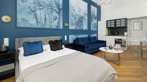 A modern bedroom with a bed, a sofa, a dining table, and a kitchen area. - Climatic Studio | Close to Market Square and Wawel Castle (Kraków)