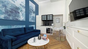 A modern living room with a blue sofa, a white coffee table, and a large window with a painting. - Climatic Studio | Close to Market Square and Wawel Castle (Kraków)