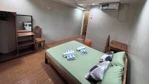Quarto com cama, guarda-roupa de madeira, uma mesinha, espelho e ar condicionado.