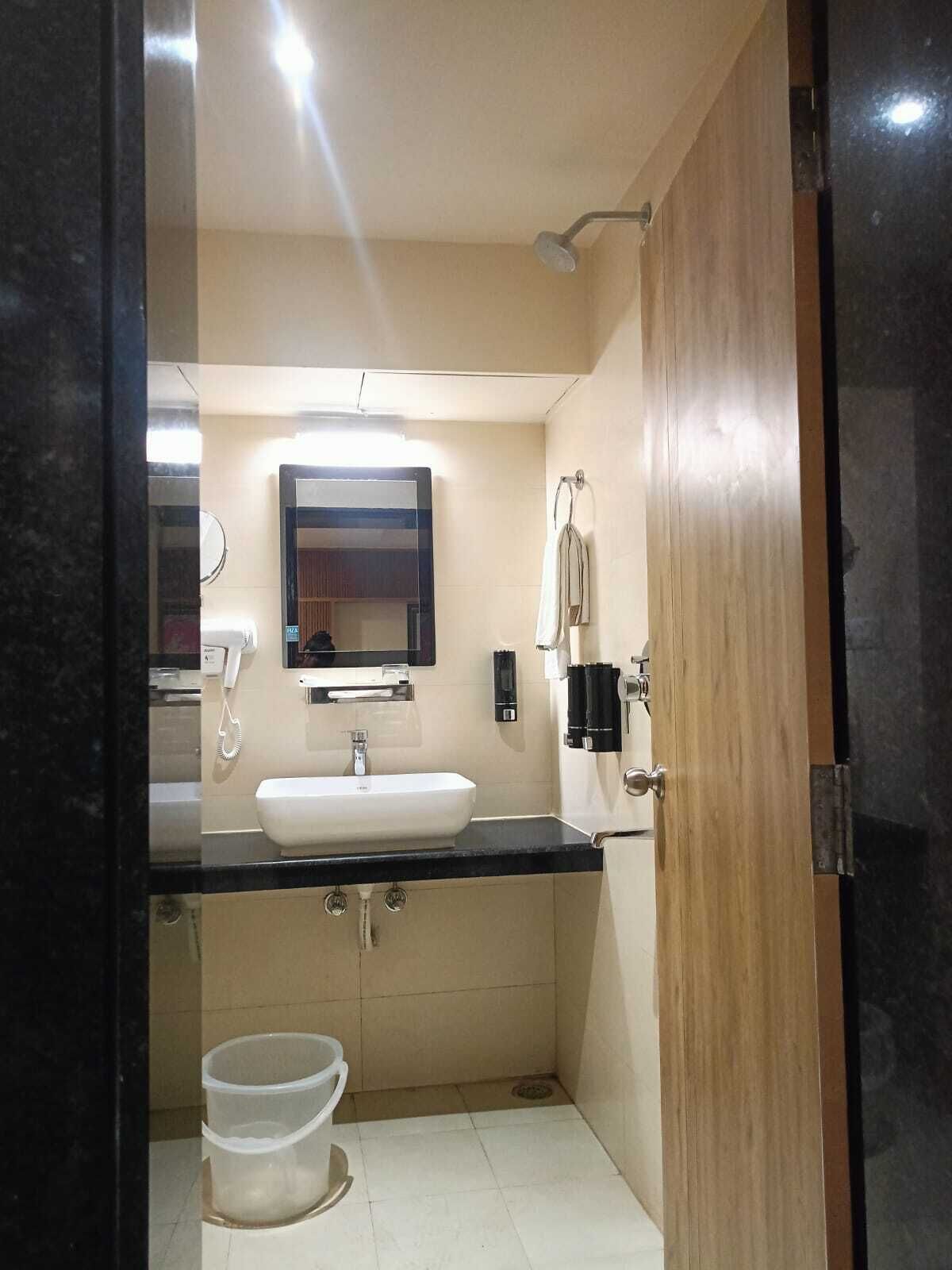 A compact bathroom with a sink, mirror, and shower.