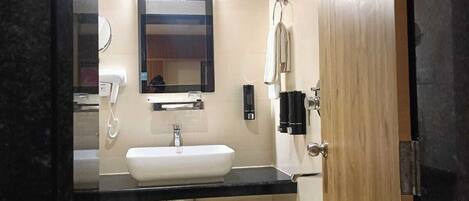 A compact bathroom with a sink, mirror, and shower.