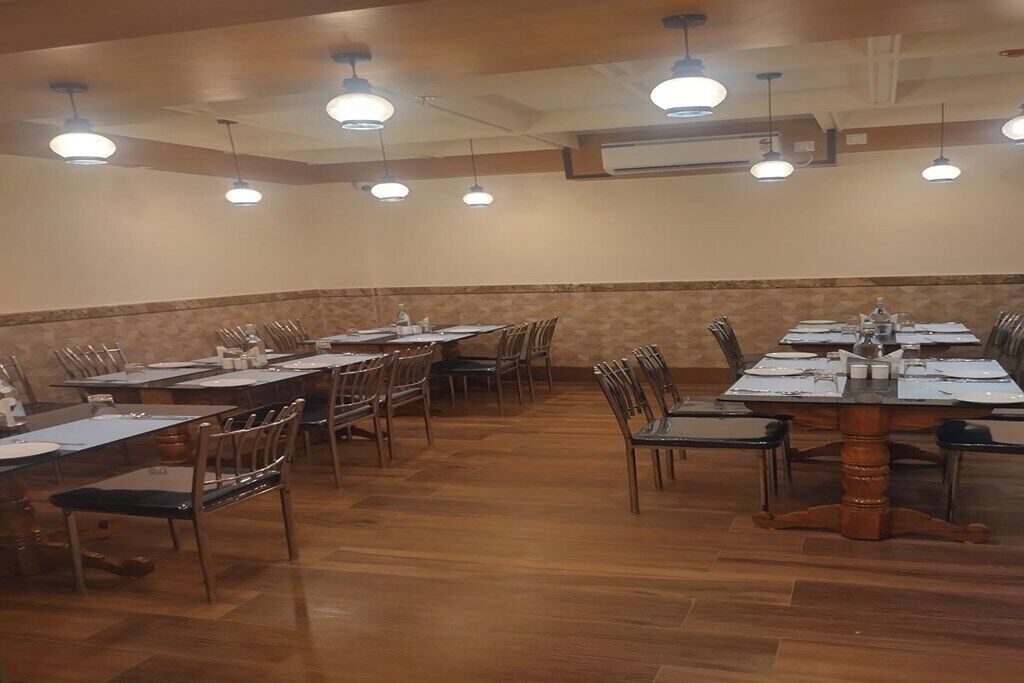 A conference room with multiple tables and chairs, equipped with overhead lighting and air conditioning.