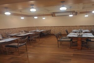A conference room with multiple tables and chairs, equipped with overhead lighting and air conditioning.