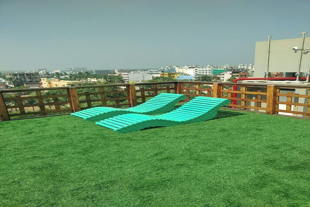 Une terrasse avec du gazon synthétique et deux fauteuils bleus.