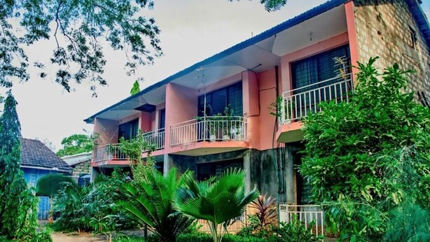A multi-story building with balconies and a garden area.