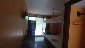 A room with a bed, a desk, and a window with curtains.