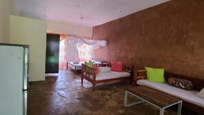 A room with a bed, a sofa, a small table, and a refrigerator.
