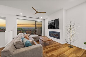 En moderne stue med en stor sofa, et træbord og et dekorativt træ.