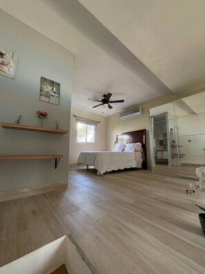 Ein Schlafzimmer mit Bett, Deckenventilator, Fenster und Spiegel.