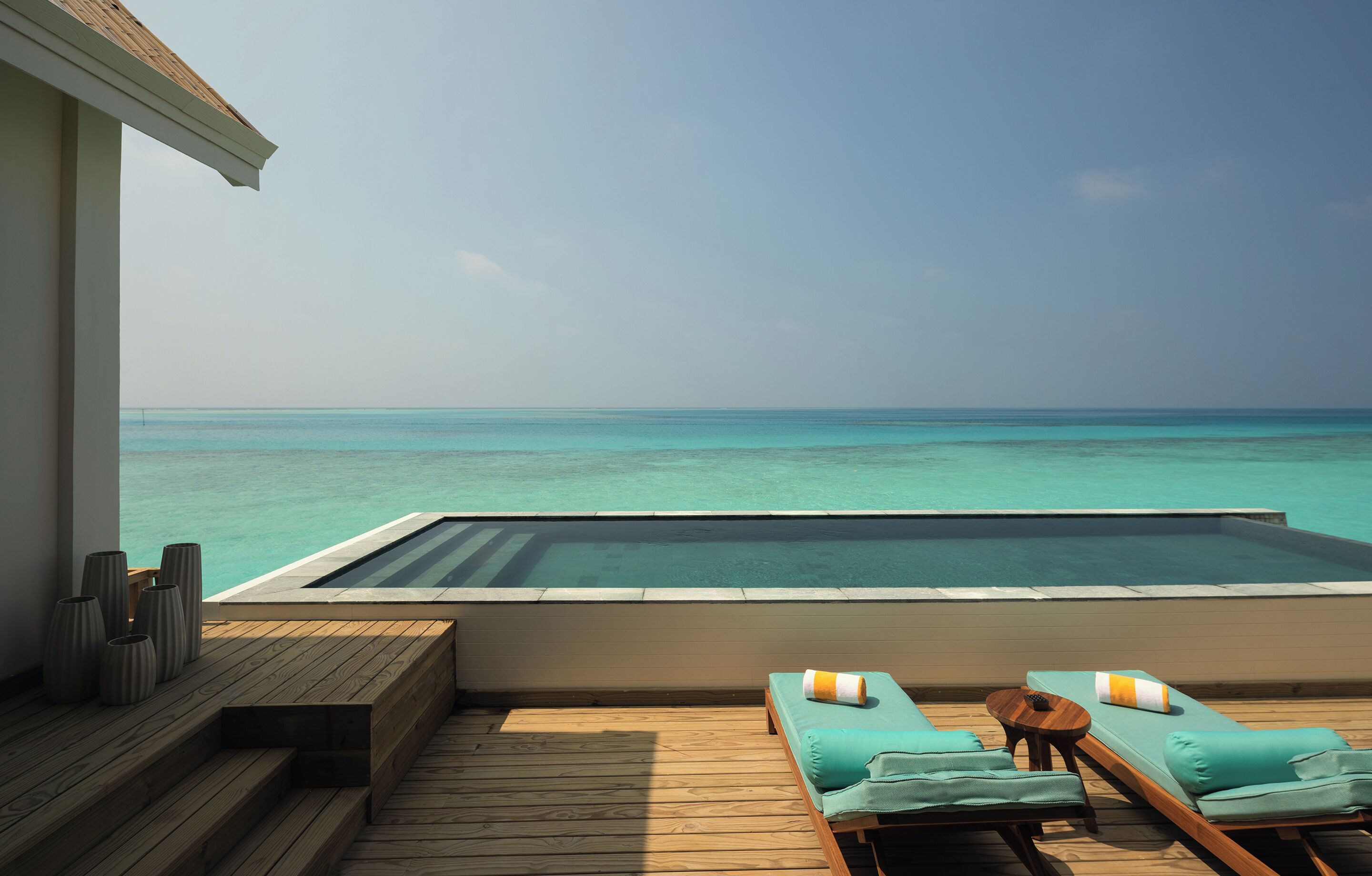A poolside area with lounge chairs and a view of the ocean.