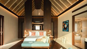 A spacious bedroom with a large bed, a sitting area with a table, and a view of a bathroom. - RAH GILI MALDIVES (Mahaanaelhihuraa)
