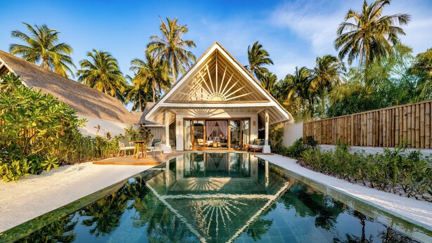 A resort with a swimming pool, palm trees, and a thatched-roof building. - RAH GILI MALDIVES (Mahaanaelhihuraa)
