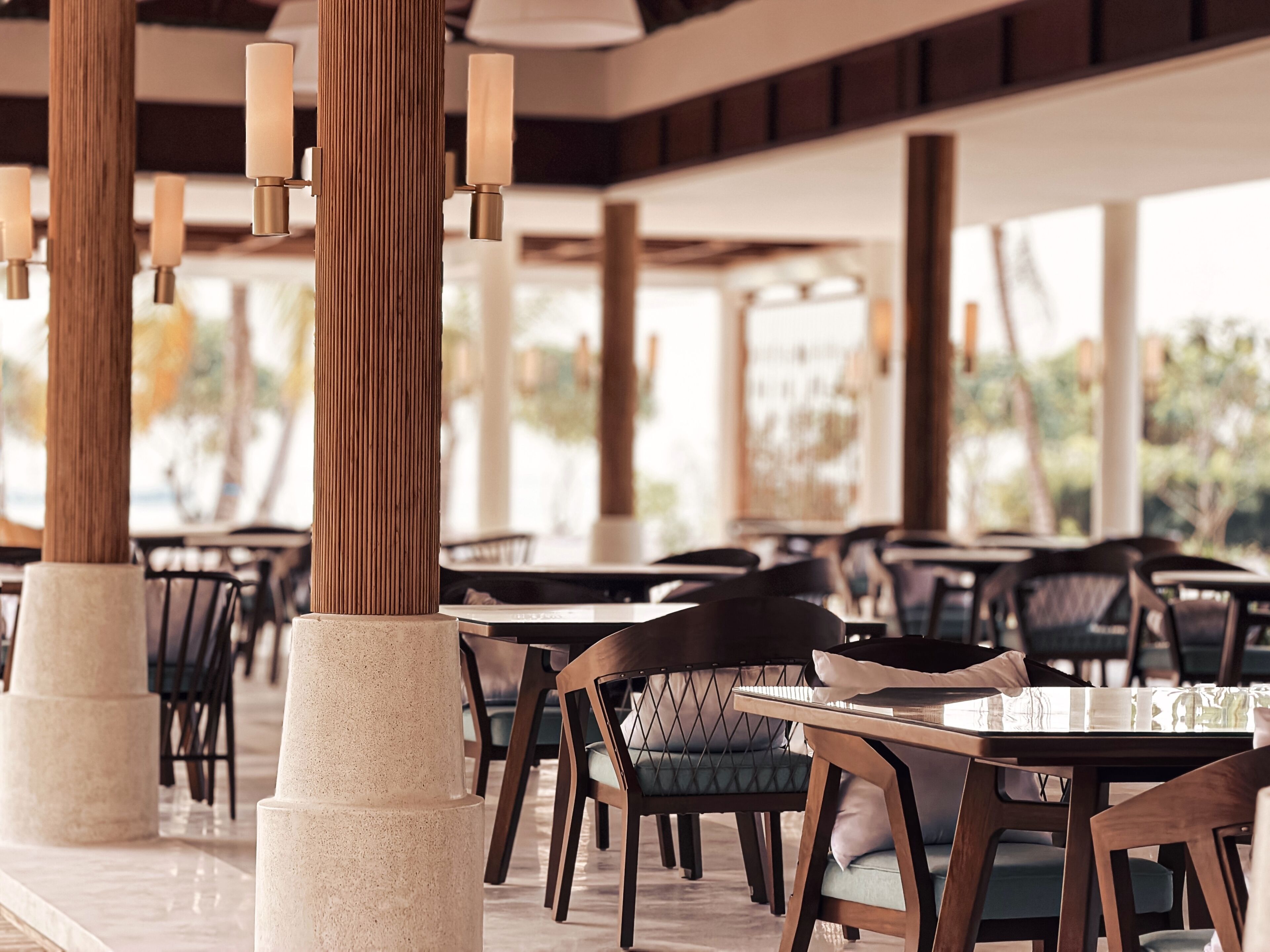 A restaurant with wooden pillars, tables, and chairs.