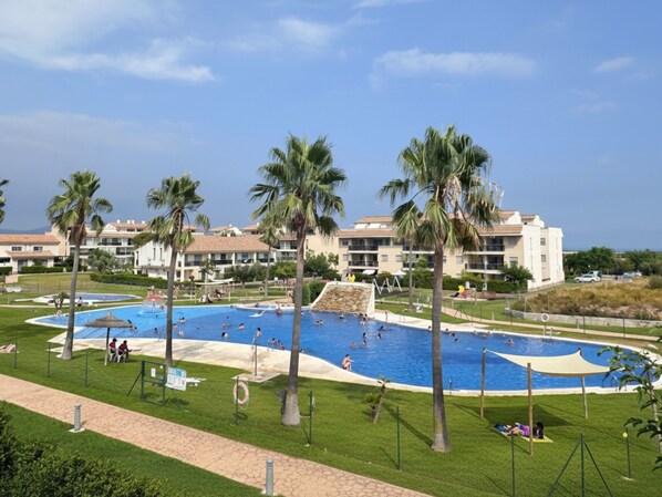 A resort with multiple swimming pools, palm trees, and a clear sky.