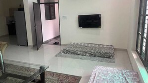Un salon avec un téléviseur à écran plat fixé au mur, un canapé et une table basse.