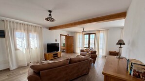 A living room with a sofa, TV, wooden flooring, and a ceiling fan. - Casa Joanna Lanzarote (Nazaret)