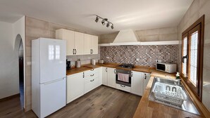 A modern kitchen with white cabinets, a wooden countertop, a built-in oven, a microwave, and a sink. - Casa Joanna Lanzarote (Nazaret)