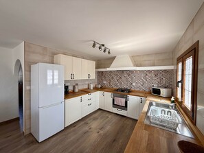 A modern kitchen with white cabinets, a wooden countertop, a built-in oven, a microwave, and a sink. - Casa Joanna Lanzarote (Nazaret)