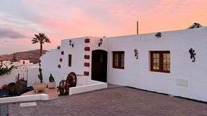 A white building with a wooden door, windows, and decorative wall elements. - Casa Joanna Lanzarote (Nazaret)