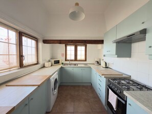 A kitchen with a washing machine, a stove, a microwave, and a sink. - Villa Ann Lanzarote (Nazaret)