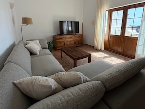 Uma sala de estar com sofá, mesa de centro, televisão e um armário de madeira.