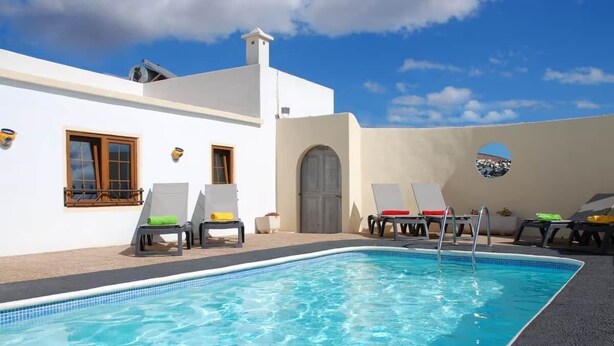 A pool area with lounge chairs and a clear blue pool. - Villa Ann Lanzarote (Nazaret)