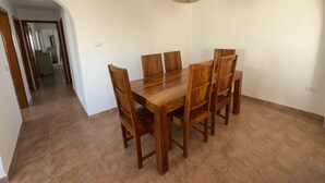 A dining area with a wooden table and chairs, a hanging light fixture, and a hallway leading to another room. - Villa Ann Lanzarote (Nazaret)